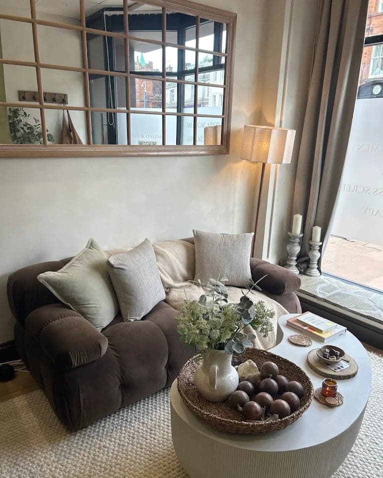 The waiting area at Cove Clinic: a brown velvet sofa, a round table and a lamp by the window