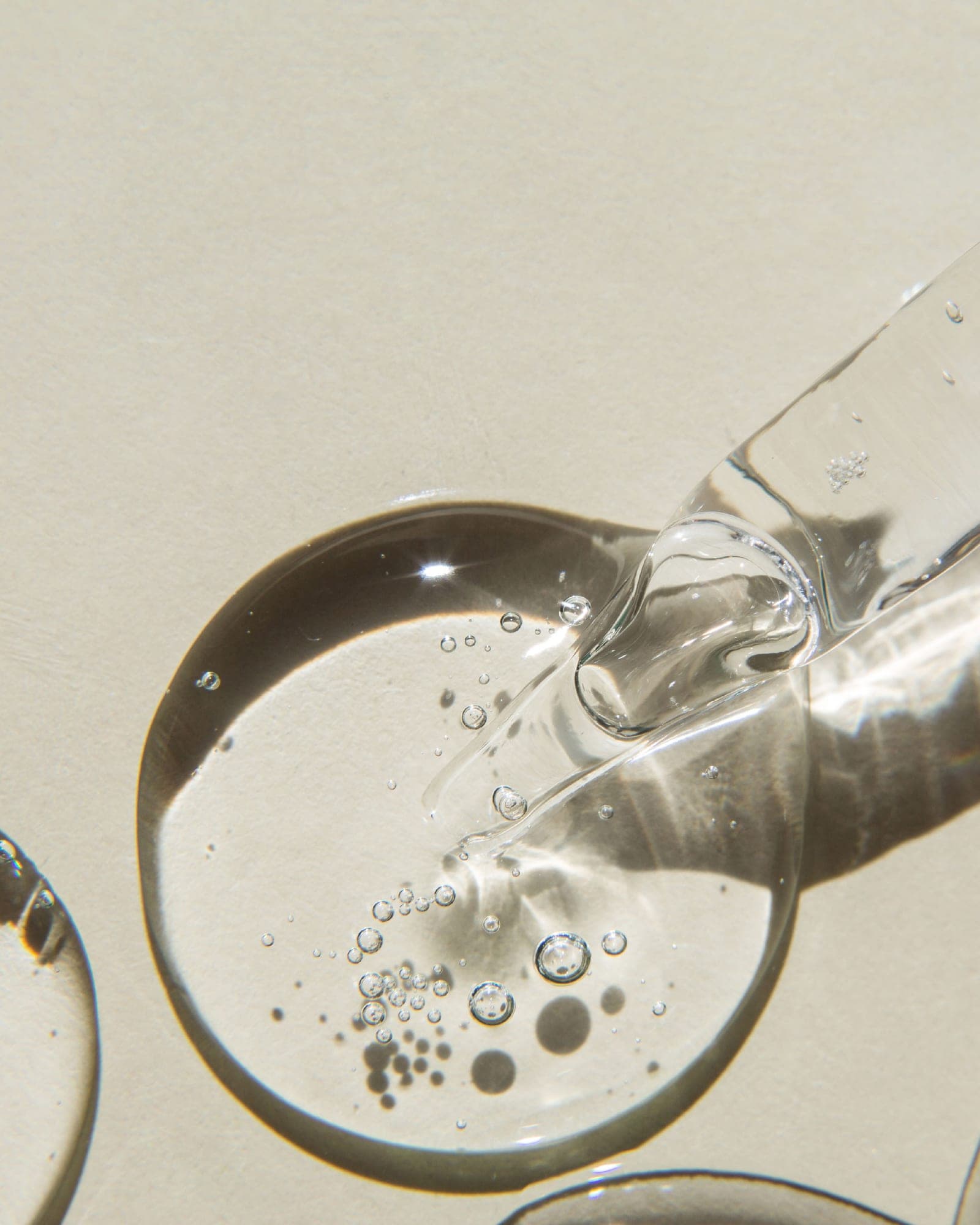 A drop of clear serum falling from a glass dropper